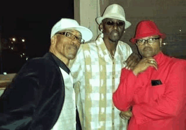 three men are posing for a picture together while wearing hats and glasses .