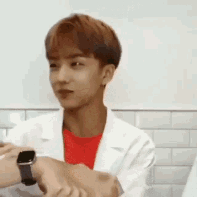 a young man in a lab coat is wearing a smart watch on his wrist .