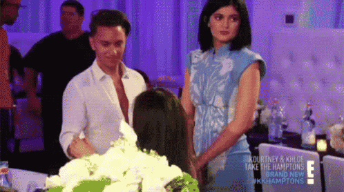 a man and a woman are standing next to each other in front of a table with flowers on it .
