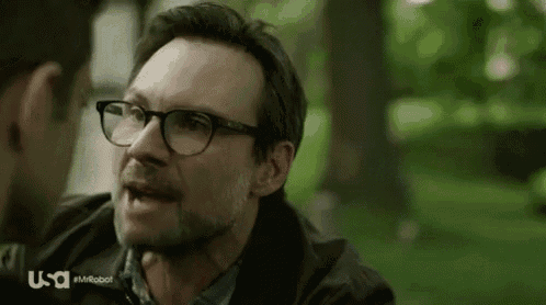 a man wearing glasses is screaming at another man in a park .