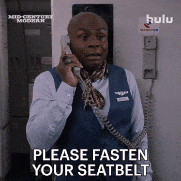 a man talking on a phone with the words please fasten your seatbelt on the bottom