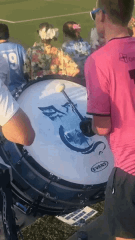 a man in a pink shirt playing a drum with evans written on it