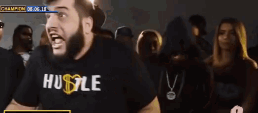 a man wearing a hustle shirt stands in front of a crowd of people