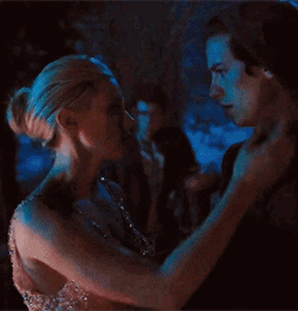 a man and a woman are dancing in a dark room . the woman is wearing a dress .