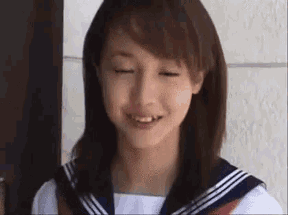 a young woman in a sailor suit is smiling and making a funny face .