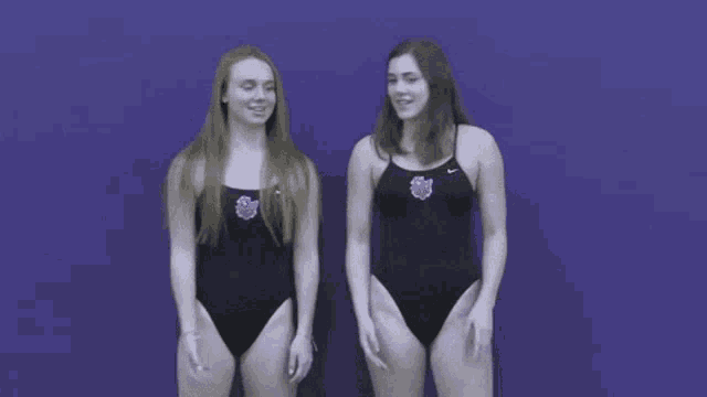 two women in swimsuits are standing next to each other on a blue background