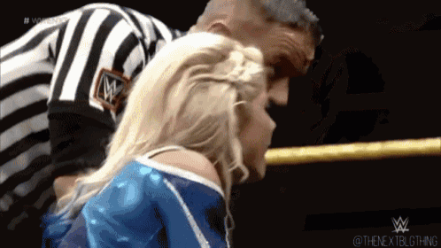 a woman in a blue and white outfit is wrestling a referee in a wrestling ring .