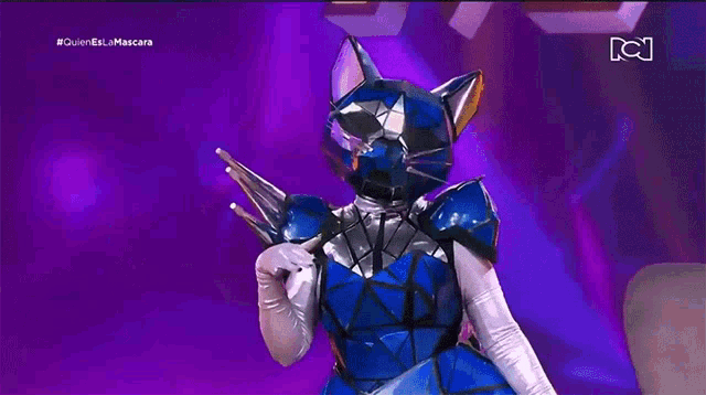 a person in a blue cat costume is holding a trophy on a stage .