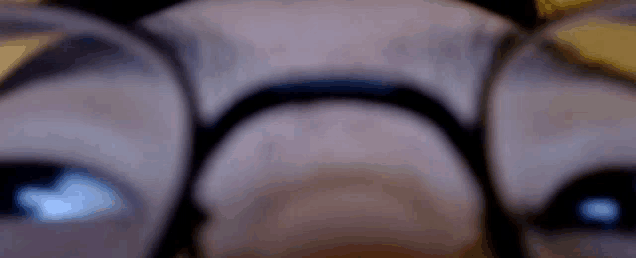 a close up of a person wearing glasses and looking at something