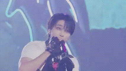 a man is singing into a microphone while wearing gloves on a stage .