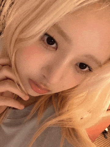 a close up of a blonde woman 's face with her hand on her chin