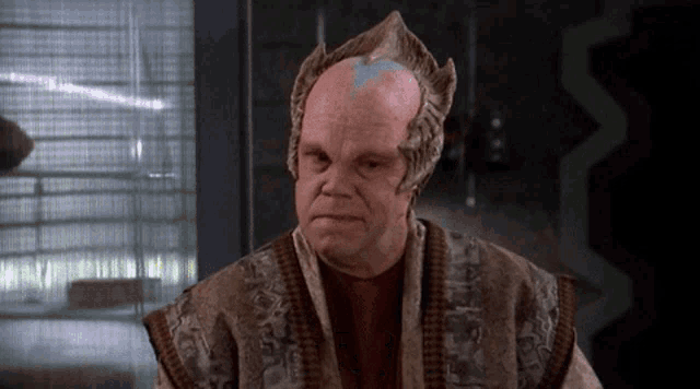 a bald man with a crown on his head and a red shirt