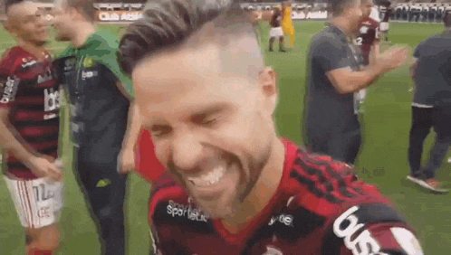 a man with a beard is smiling on a soccer field while a group of people applaud .