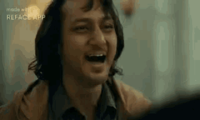 a close up of a man laughing with his mouth open in a room .