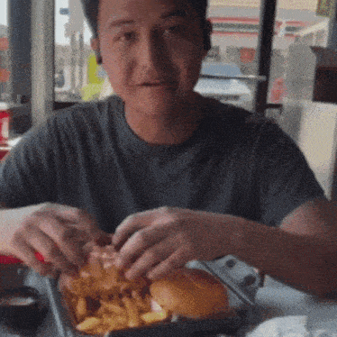 a man is eating a hamburger and french fries in a restaurant