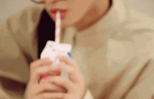 a close up of a person drinking from a carton with a straw .