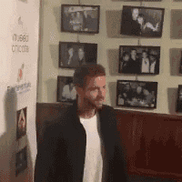 a man is standing in front of a wall with pictures on it