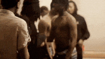 a man without a shirt is standing in a crowd of people