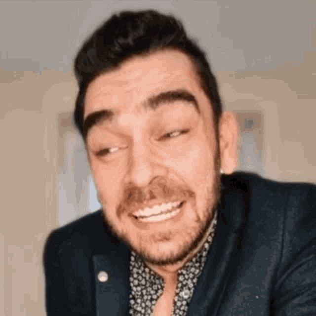 a man with a beard wearing a suit and a floral shirt is smiling