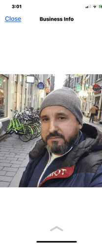a phone screen shows a man taking a selfie and says business info