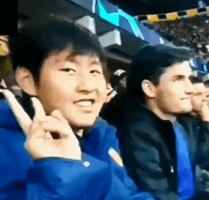 a group of people are sitting in a stadium and one of them is giving a peace sign