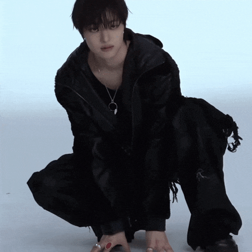 a person wearing a black jacket and pants kneeling down