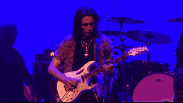 a man playing a guitar on a stage with a blue background