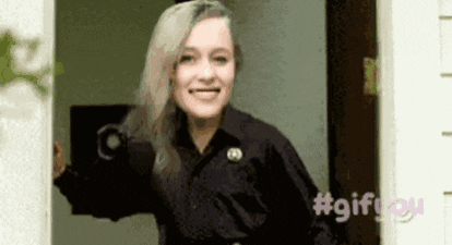 a woman in a black shirt is standing in a doorway smiling .