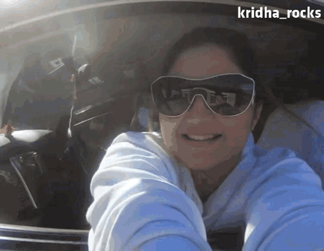 a woman wearing sunglasses is taking a selfie in a car with the name kridha_rocks on the bottom