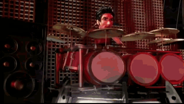 a man is playing a drum set in front of a wall of speakers