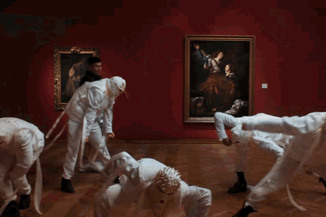 a group of people are dancing in a room with a painting in the background