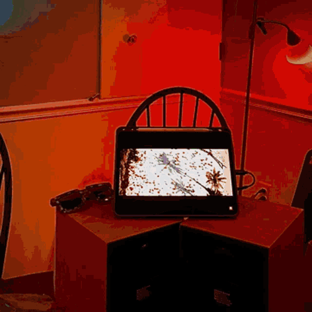 a tablet sits on a table next to a chair and sunglasses