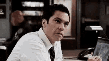 a man is sitting at a desk in front of a laptop computer .