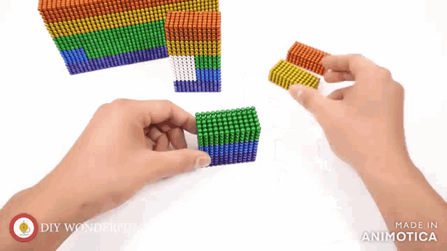 a person is playing with a rainbow colored set of magnetic beads