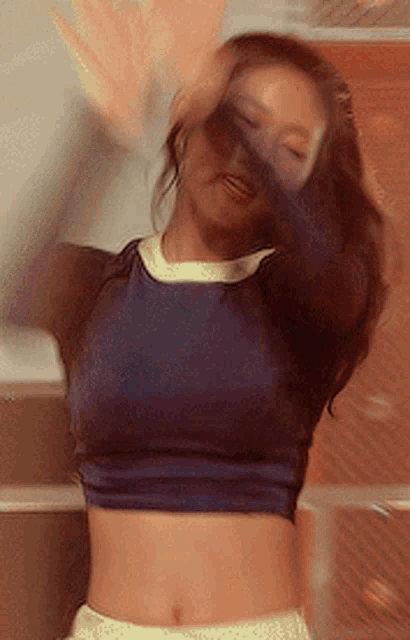 a woman wearing a blue crop top is dancing