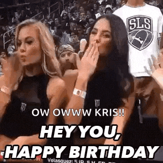 two women are sitting in the stands at a basketball game and one of them is blowing a kiss to the other .