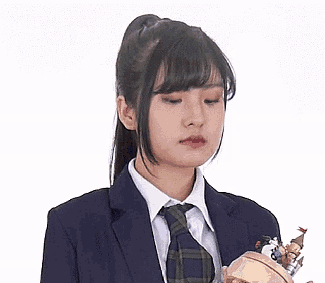 a woman in a suit and tie is holding a small toy