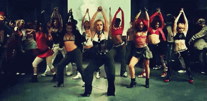 a group of women are dancing on a stage in a dark room .