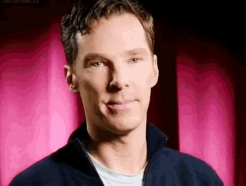 a close up of a man 's face with a pink curtain behind him .