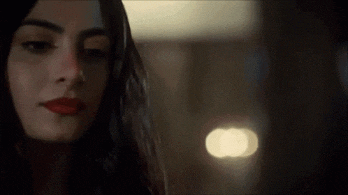 a close up of a woman 's face in a dark room with a blurry background .