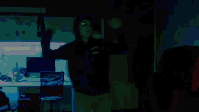 a man in a hoodie and sunglasses is dancing in a room