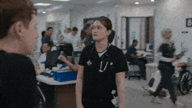 a woman with a stethoscope around her neck talks to a man in a hospital room