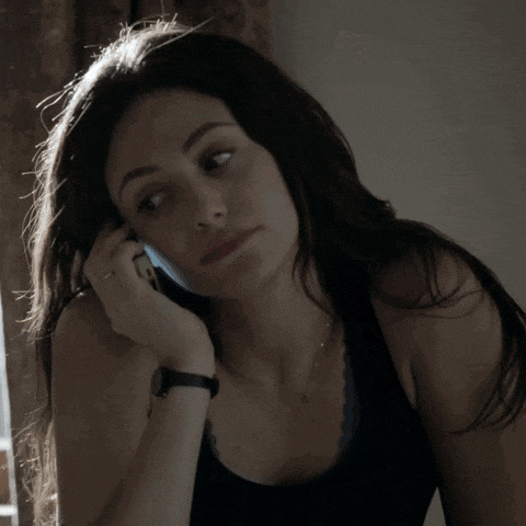 a woman in a black tank top is talking on a phone