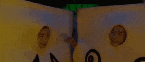 a couple of people are standing next to each other in a room with their faces sticking out of boxes .