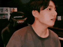 a young man is sitting in a gaming chair with the word arena on it .
