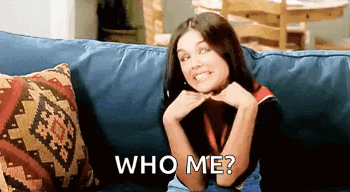a woman is sitting on a couch and asking who me ?