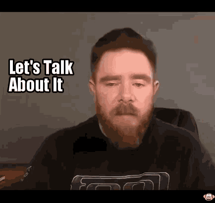a man with a beard and mustache is sitting in a chair and talking to someone .