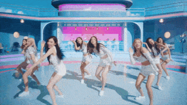 a group of young women are dancing in front of a pink and blue building