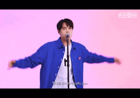 a man in a blue jacket is singing into a microphone with his arms outstretched .