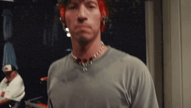 a man with red hair is wearing a gray shirt and a necklace .
